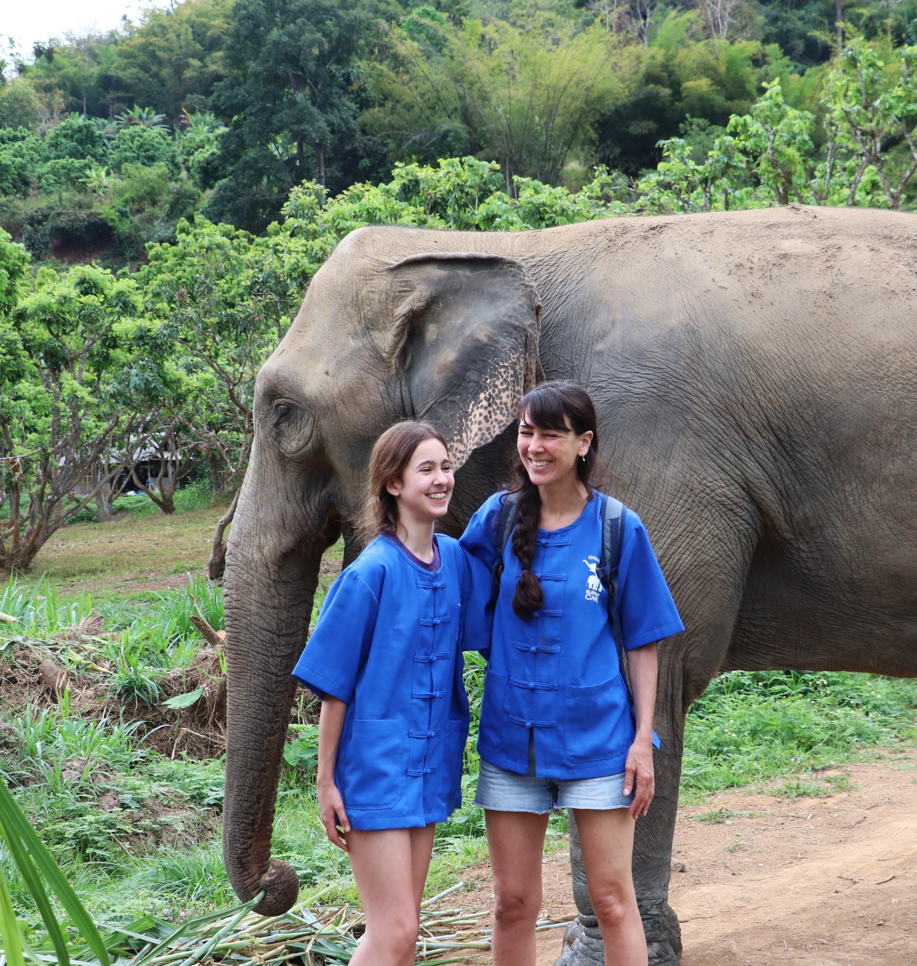 two happy guests standing with elephant at ethical sanctuary in Chiang Mai Thailand